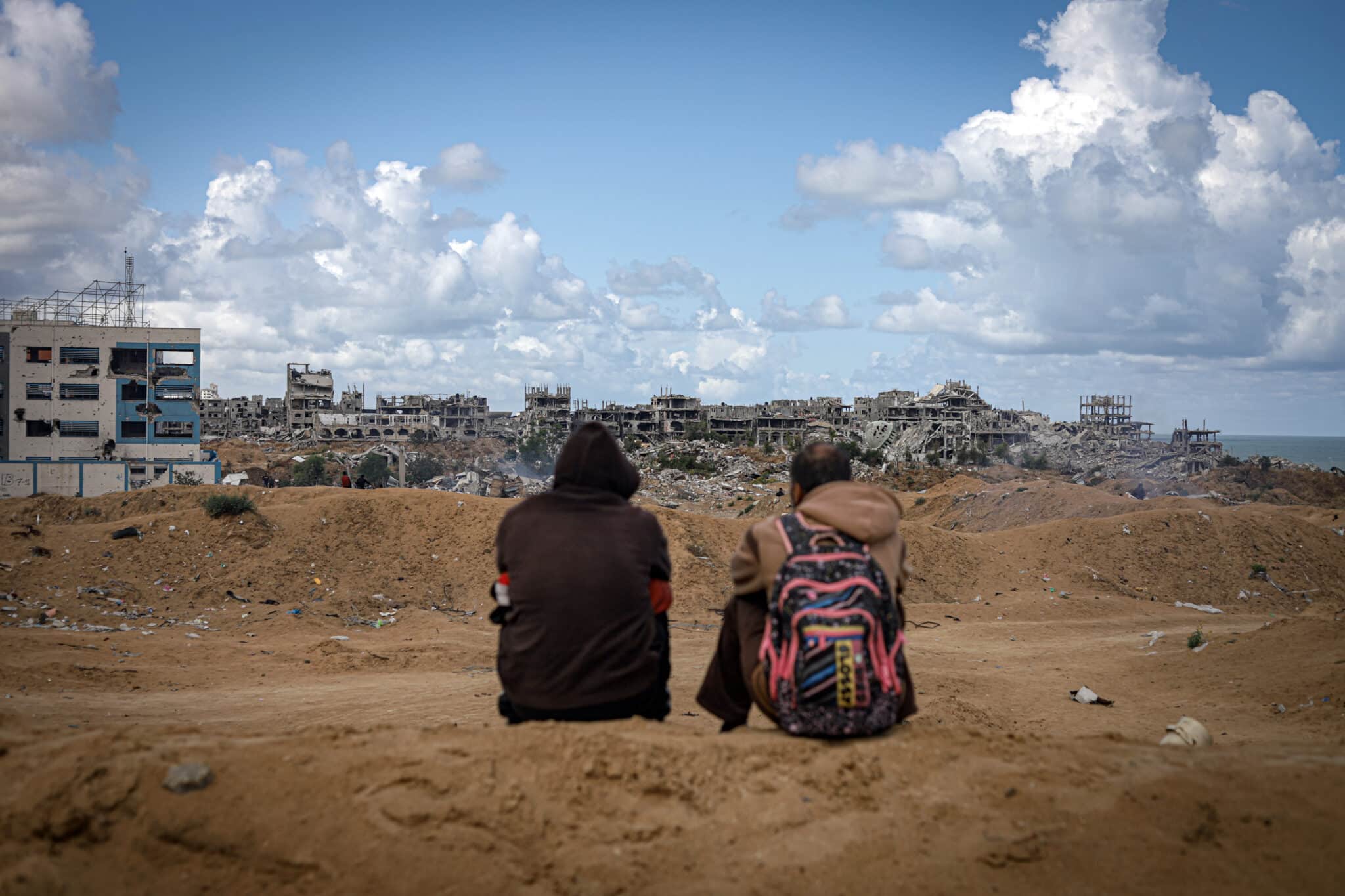 Dos hombres esperan la llegada de ayuda humanitaria en avión en una playa de la Franja de Gaza © Fátima Hassouna / Plan International